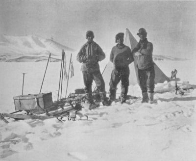 A photograph of Cherry-Garrard, Keohane, and Atkinson standing in the snow, next to a sled and a tent.