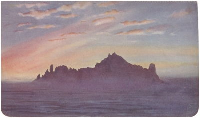 A rocky island, shaded against the sunset.