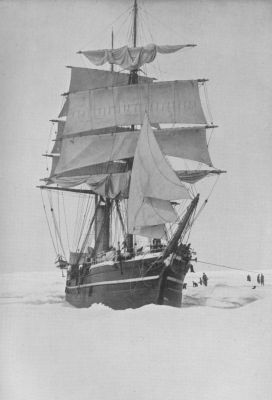 A photograph of a sailing galleon surrounded by ice. Men on the ice have ropes attached to the ship.
