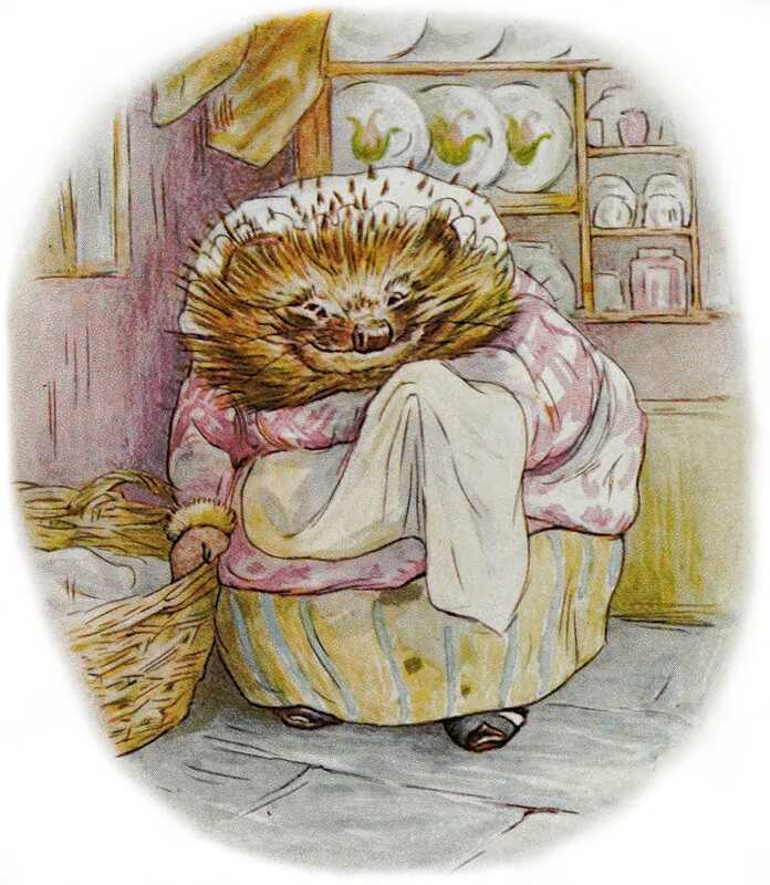 Mrs. Tiggy-winkle is wiping her left paw on her apron, and smiling. In her other paw she’s holding a basket of linen. Behind her are shelves displaying her best china: white plates, plates painted with birds, and matched pink cups and saucers.
