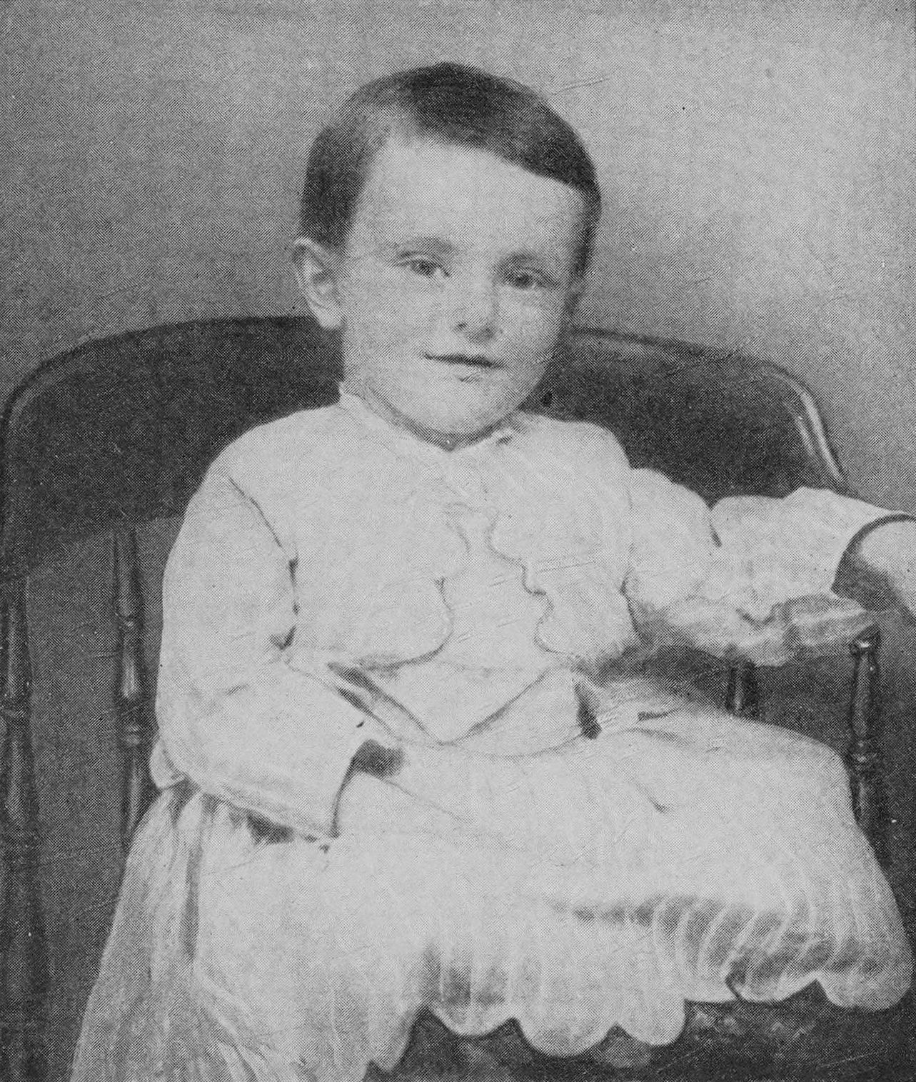 A photographic portrait of baby Calvin Coolidge in a white dress.