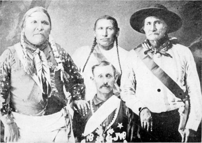 A photographic portrait of four men, with Lone Wolf on the left and Geronimo on the right; in the middle is a Western man wearing decorated military dress.