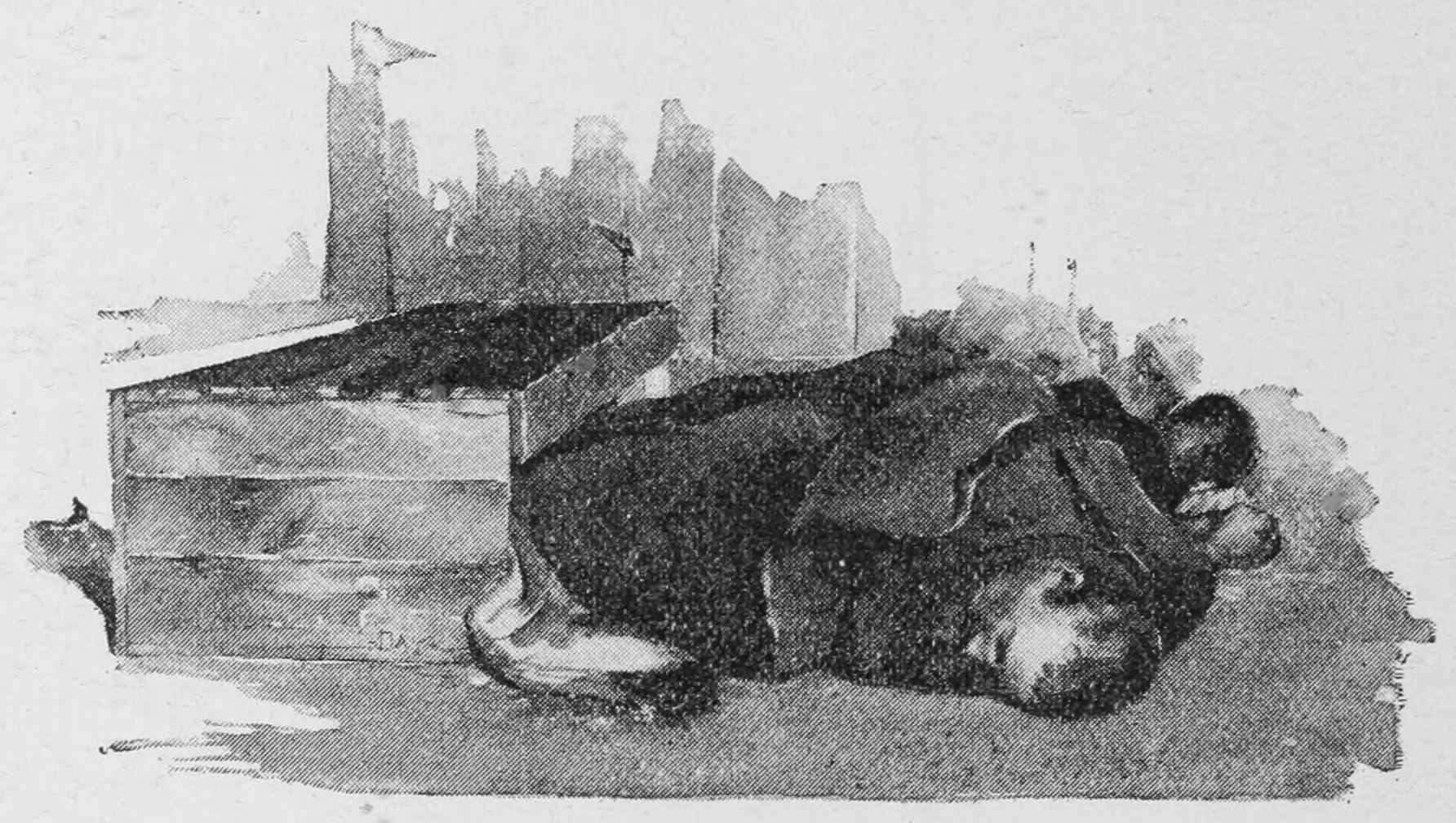 A man is curled up on the ground with his feet in a box, sleeping.