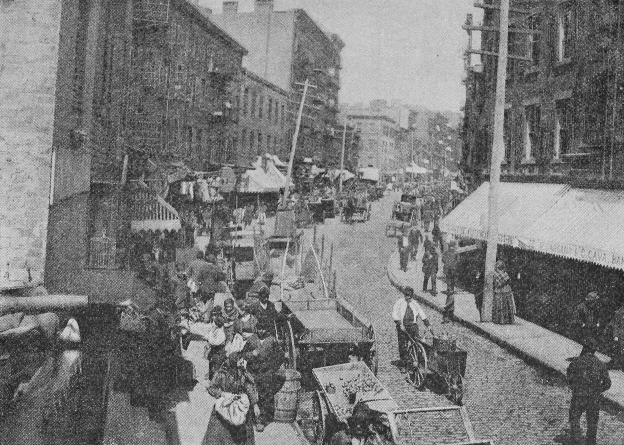A busy street, lined with buildings, is filled with carts and pedestrians. The street curves off to the right.