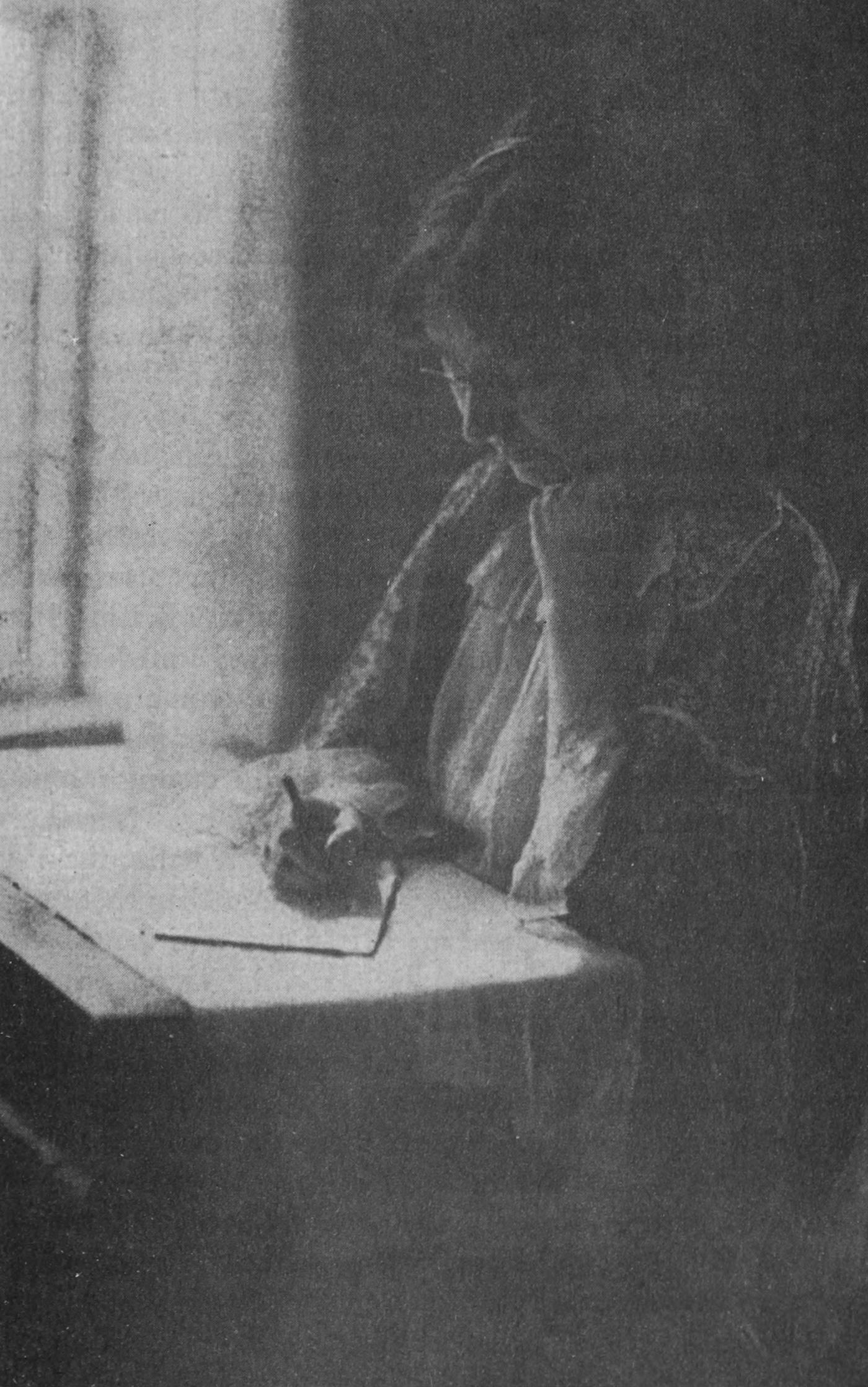 A photograph of Ellen Gates Starr seated at a desk, writing a letter.