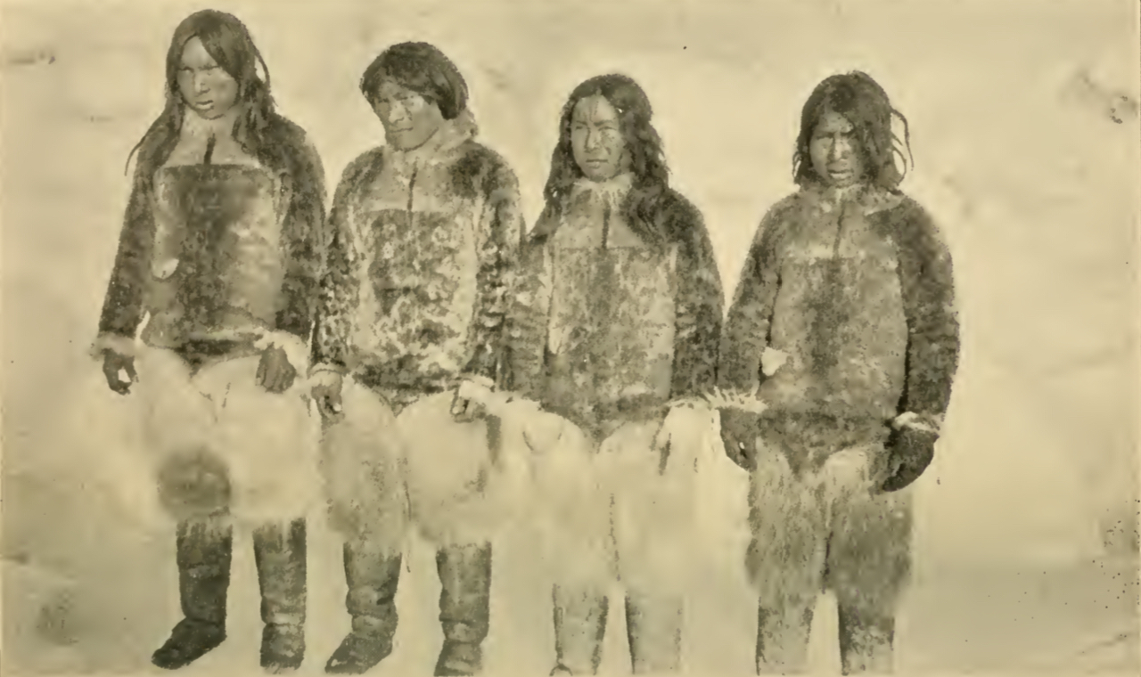 Four eskimos standing side-by-side in a snowy background.