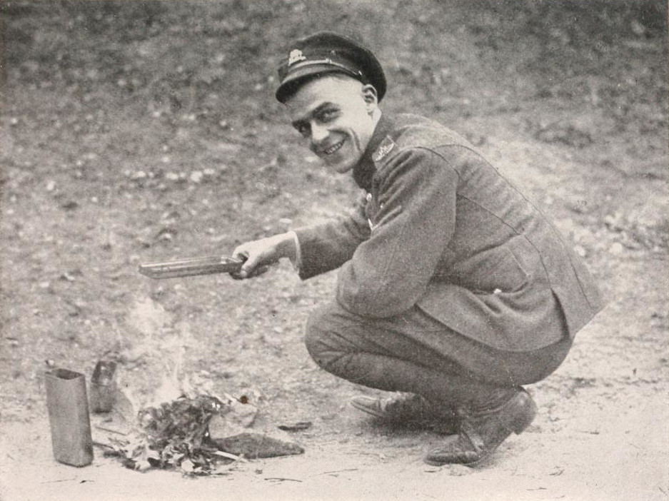 A soldier is holding a tin and crouching over a fire on the ground.
